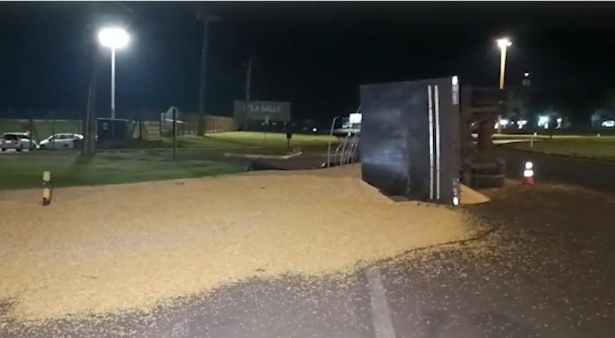 Carreta carregada com milho tomba em rotatória e espalha carga sobre a pista
